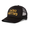 Black six-panel trucker hat shown from a front three-quarter angle with a curved bill. The front foam panel features a yellow screen-printed "GALLERY DEPT." English logotype displayed upside down. Black mesh side and back panels are visible.