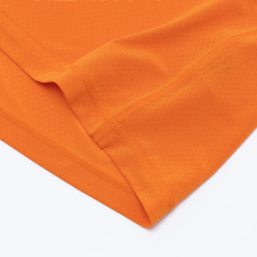 Close-up of the orange athletic T-shirt fabric, showing the tonal stitching along the seams, folded hem construction, and fine perforations throughout the breathable material. Displayed against a plain white background.
