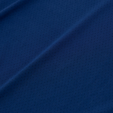 Close-up of the navy blue athletic fabric, showing its fine perforated texture and subtle diagonal folds.