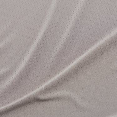 Close-up of the taupe athletic tank top fabric, highlighting the fine perforations, subtle knit texture, and soft folds of the breathable material.