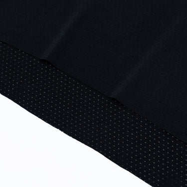 Close-up of the lower hem of a black athletic T-shirt, showing the perforated fabric panel, subtle tonal stitching, and the fine texture of the breathable material.
