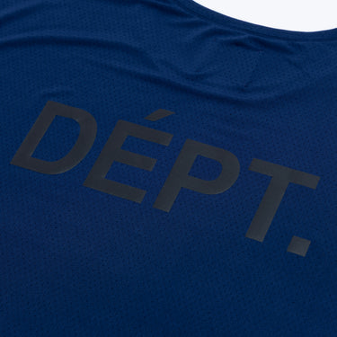 Close-up of the enlarged dark “DÉPT.” logotype on the back of a navy blue athletic T-shirt, highlighting the printed lettering and the fine perforated texture of the fabric.