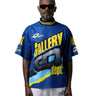 Model wearing black sunglasses, a blue short sleeve mock neck jersey with oversized yellow and grey "GALLERY DEPT." graphics across the front, light grey sweatpants, and black shoes.