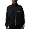 A man modeling a black track jacket with white side stripes and white logo details, on a white background.