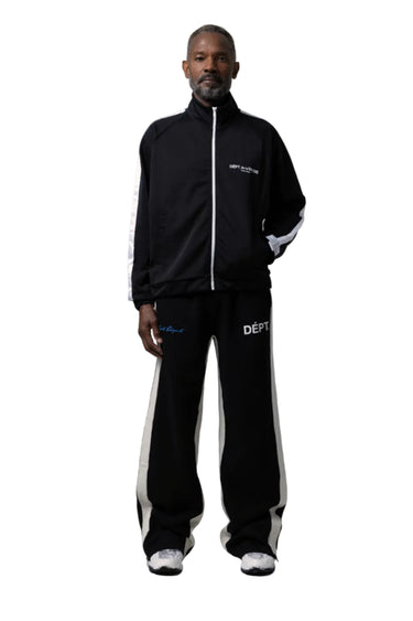 A man modeling a black tracksuit with white side stripes and white logo details, on a white background.