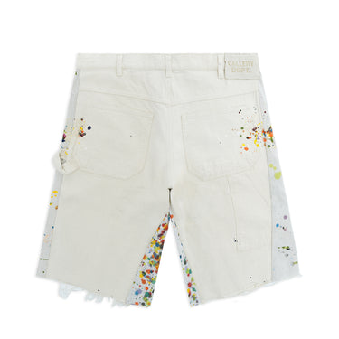 Back view of a long, baggy carpenter shorts laid flat against a white background, featuring an off-white back with two patch pockets, multicolored paint splatters along the pockets and contrasting light gray side panels, a carpenter-style utility pocket, a back waistband patch reading “GALLERY DEPT.”, and frayed hems.