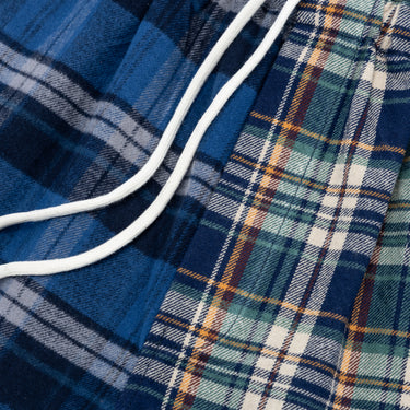 Close-up of the center front of the plaid shorts, showing the white drawstrings over the contrasting navy and blue plaid panels, with the green, white, and orange plaid panel.