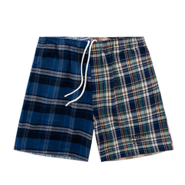 Front view of blue plaid athletic shorts laid flat against a white background, featuring contrasting navy and light blue plaid panels, an elastic drawstring waistband with white drawstrings, above-the-knee length, and a subtle “GALLERY DEPT.” logotype in black near the hem.