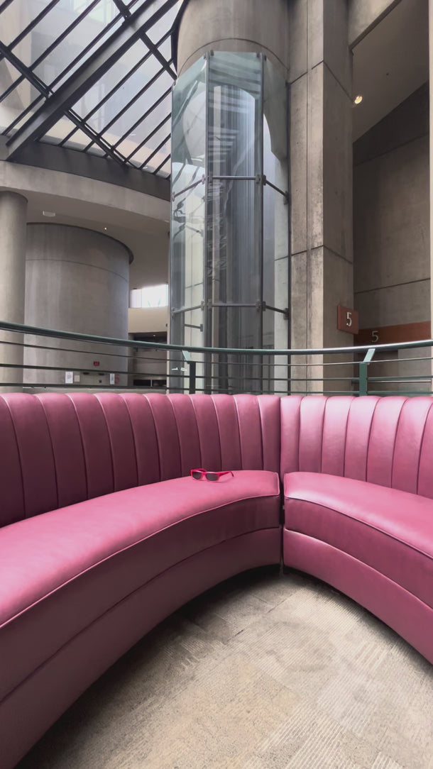 Video of red sunglasses with dark gray lenses perched on a pink leather booth with an active elevator in the background.